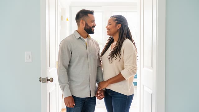 Married couple standing together in a bright home doorway